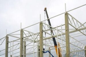 Imagem de montagem de estruturas metálicas especiais em oficina industrial, com peças robustas e técnicos em ação, destacando a experiência da Femes em soluções metálicas.